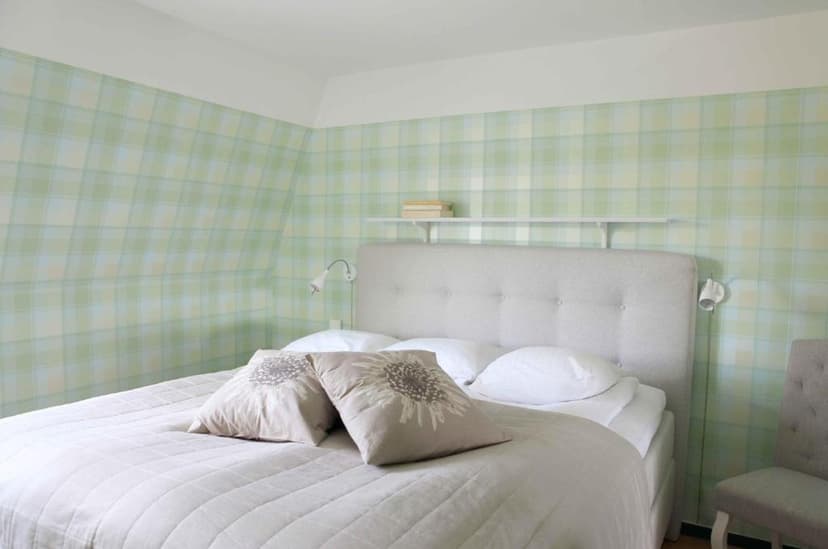 Bedroom at Agda Lund Bed & Breakfast with green plaid wallpaper and white bedding.