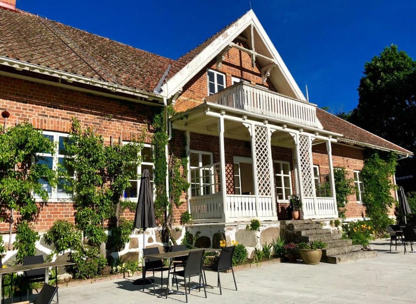 Brick residence with white porch and outdoor dining patio under blue sky