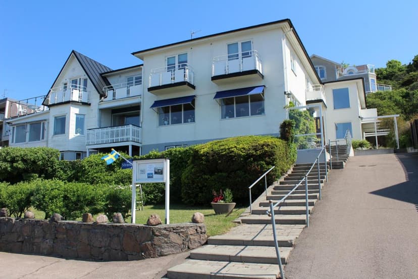 White Pensionat Strandgården building with balconies, blue awnings, and Swedish flag on a sunny day.