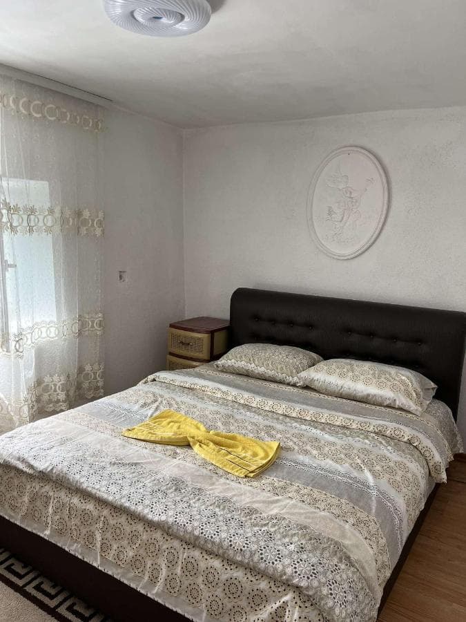 Guest House GURI room with double bed, patterned bedding, and white sheer curtains.