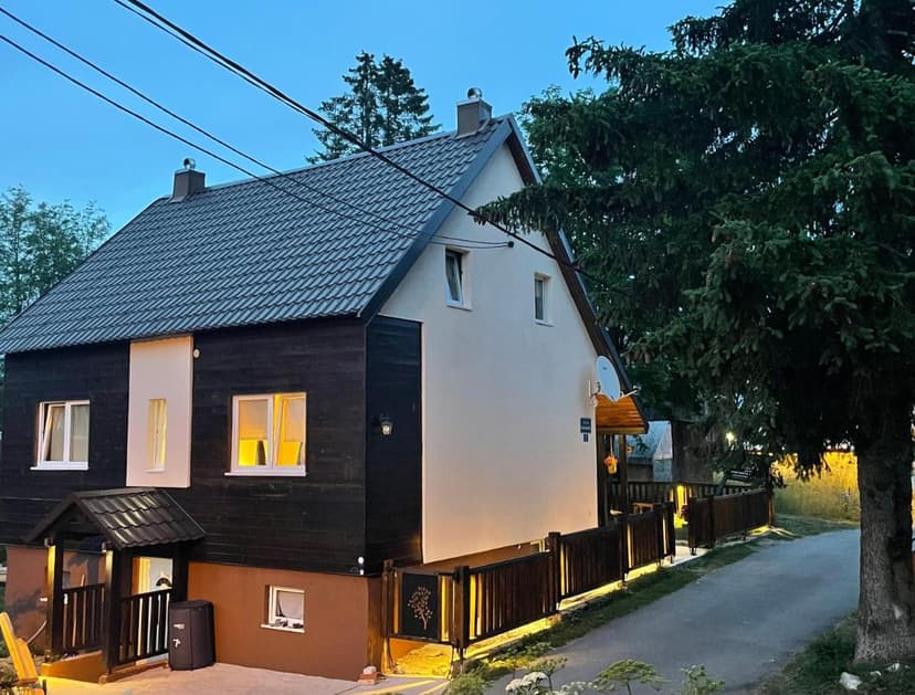 Guest house with dark wood siding and illuminated windows near Durmitor mountains.