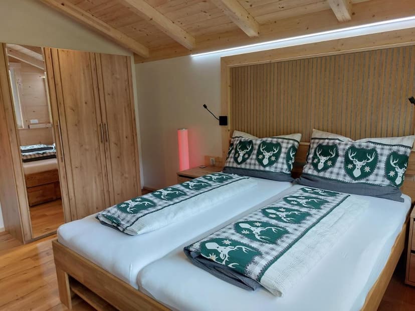 Twin beds with deer motif bedding in a room with wood paneling and closet