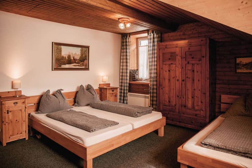 Cozy wooden attic bedroom with twin beds, plaid curtains, and rustic furniture