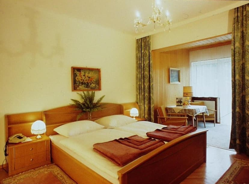 Twin beds with white linens in a hotel room with wood furniture and chandelier.