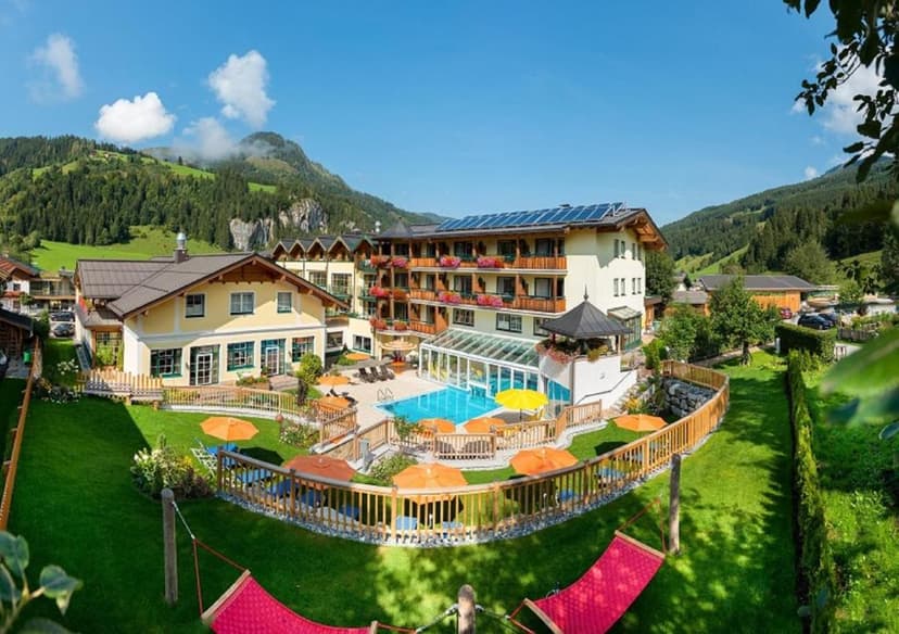 Hotel Guggenberger with outdoor pool, sun loungers, and hammocks in a green mountain valley.