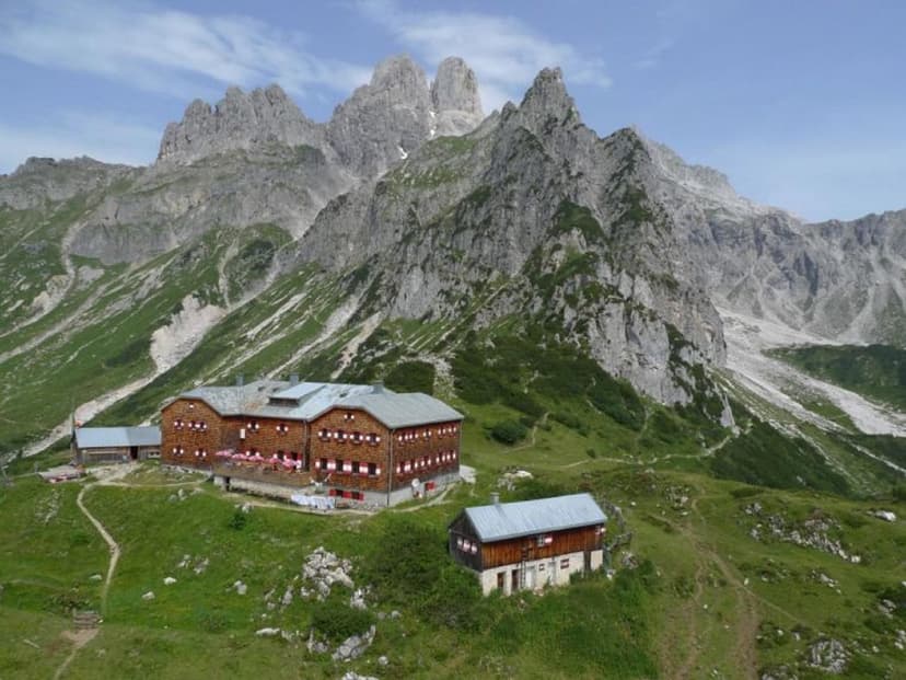 Hofpürglhütte mountain hut nestled in green alpine meadow below jagged rocky peaks
