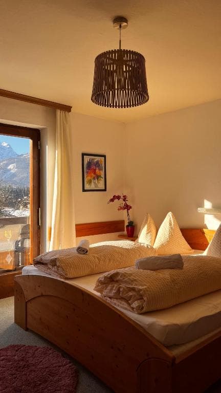 Cozy hotel room with wooden bed, mountain view through window, and woven light fixture