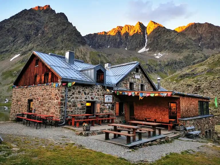 Winnebachseehütte stone mountain hut with outdoor seating against sunlit alpine peaks