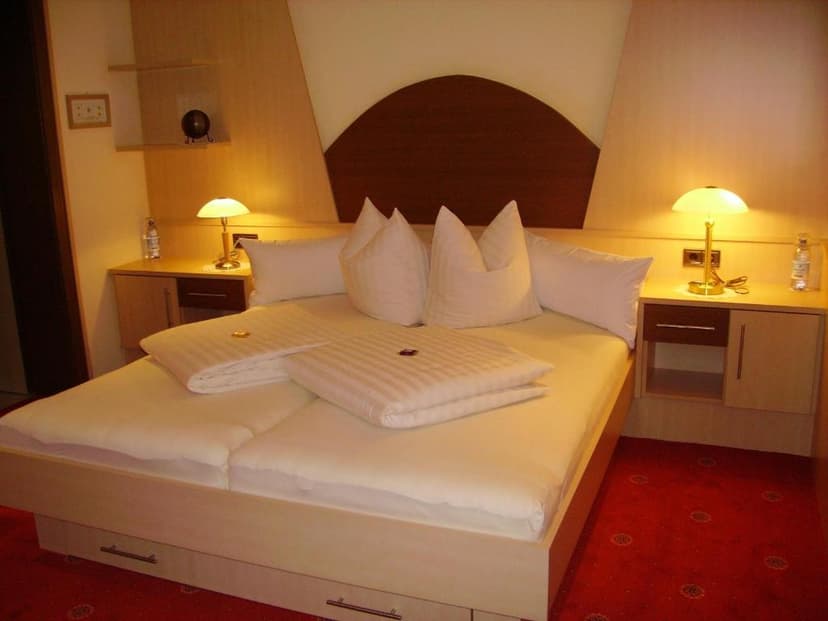Twin beds made up with white linens, illuminated by bedside lamps in a guest room.