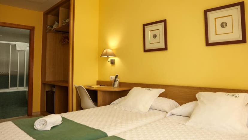 Twin hotel room with yellow walls, white bedding, and an open closet next to the bathroom entrance.
