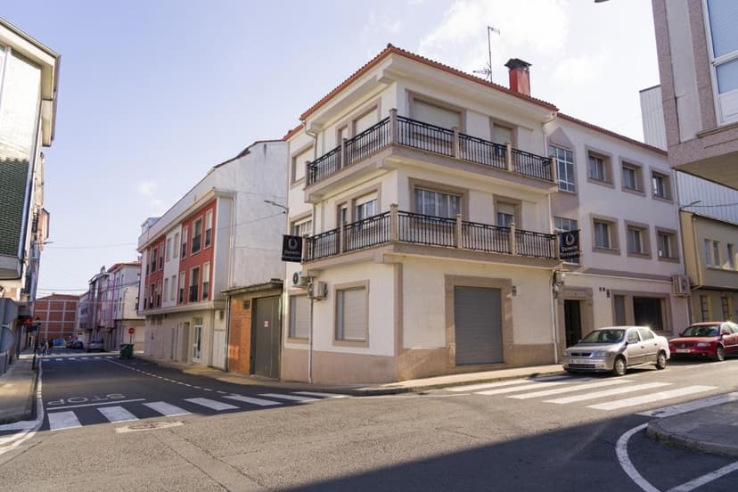 Corner building with balconies, Pension Ferradura sign, on a street corner with cars.