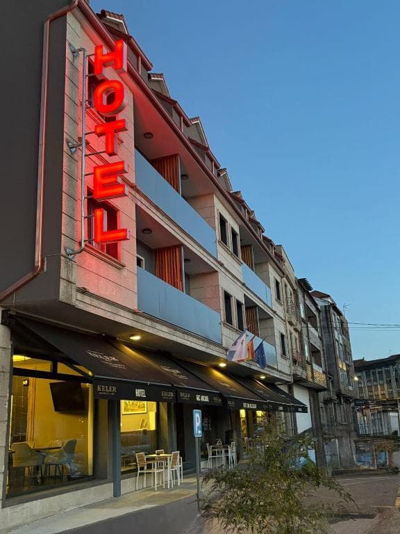 Hotel Keler with vertical red neon sign on building facade in a city street at dusk