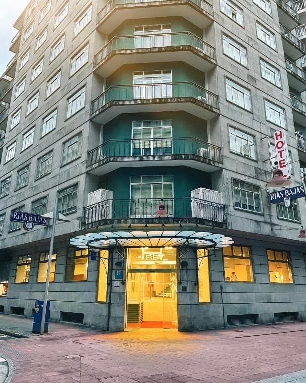 Hotel Rías Baixas building exterior with illuminated entrance and street signs on a city street.