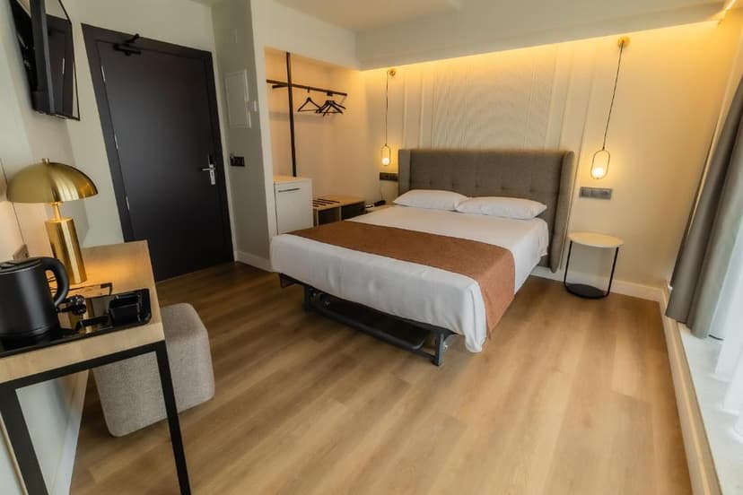 Hotel Corona de Padrón bedroom with double bed, wood floor, and modern lighting.