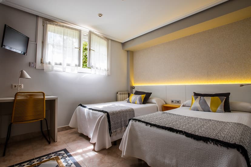 Twin bedroom with white bedding, yellow accents, and bright window light in Zumardi Pentsioa