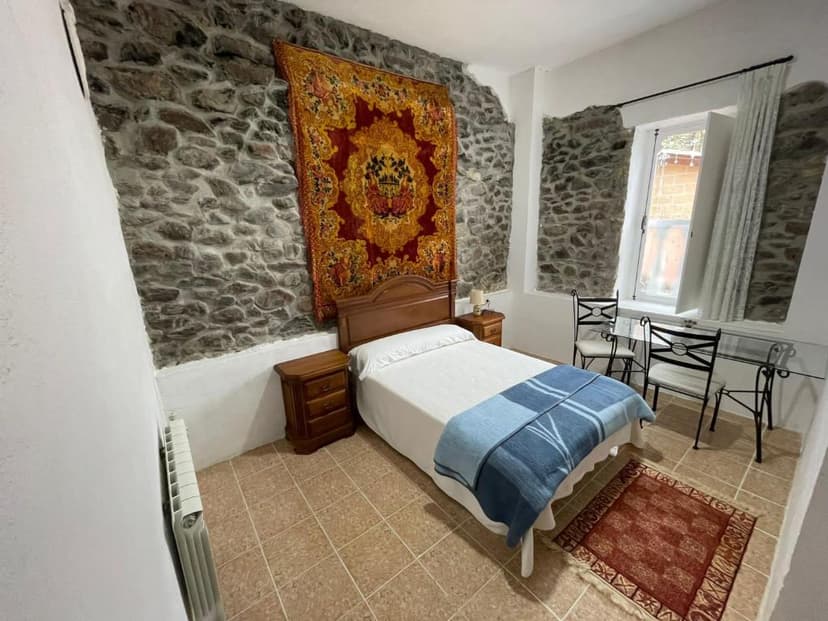 Bedroom with stone accent walls, wooden bed, and large tapestry at Hotel El Nuevo Semellon.