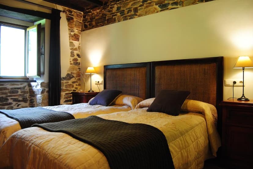 Twin beds in rustic room with exposed stone walls and bedside lamps, Apartamentos Rurales Ca Lulón