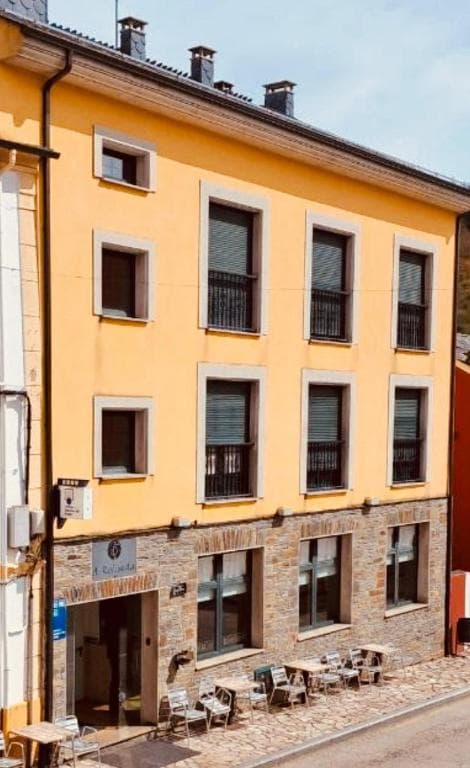 Hotel A Reigada building with yellow facade, stone base, and outdoor seating area