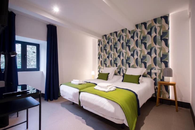 Twin beds with white linens and lime green accents in a modern room at Hotel O Cruce do Burgo.