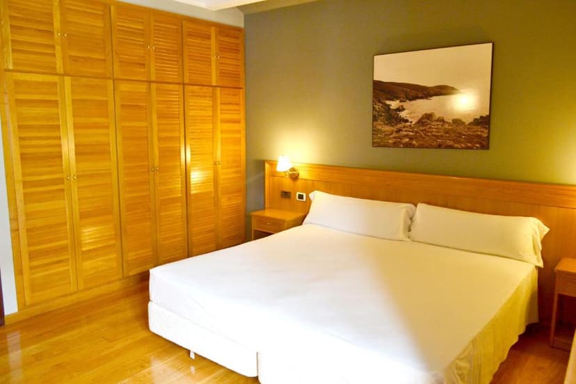Hotel room with white bedding, wooden floor, and large slatted wardrobe, Hotel Alda El Suizo.