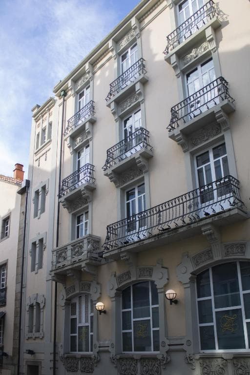 Hotel Alda El Suizo building facade with ornate balconies and windows under a blue sky.