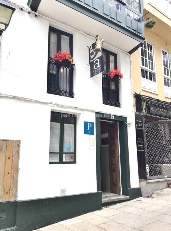 White building entrance with green trim, "Apilladeira" sign, and flower boxes on balcony.