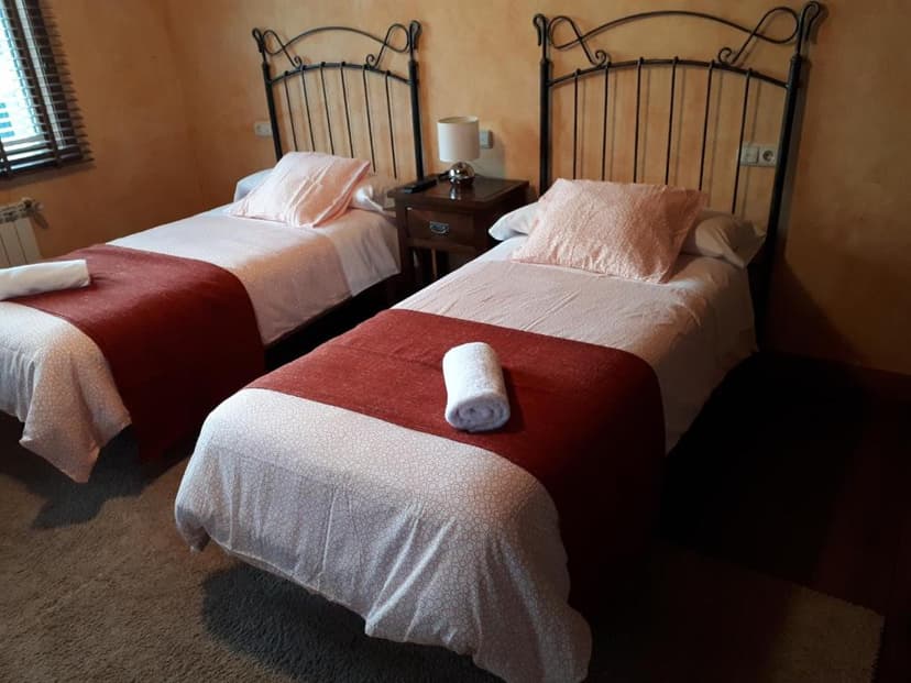 Twin beds with wrought iron headboards in a room with warm orange walls and dark wood furniture.