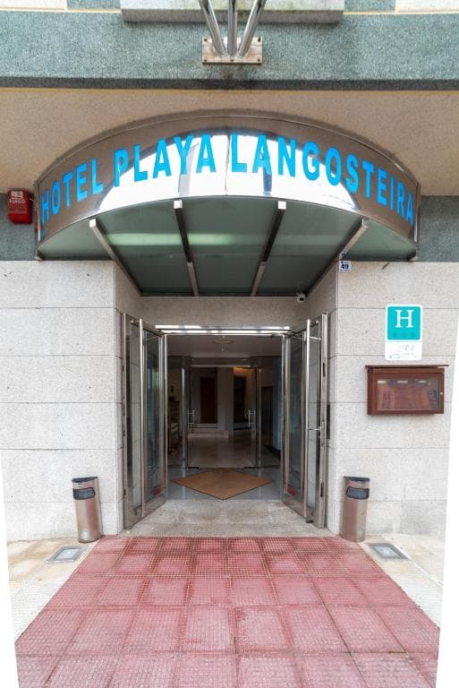 Entrance of Hotel Playa Langosteira with curved metal awning and open glass doors.
