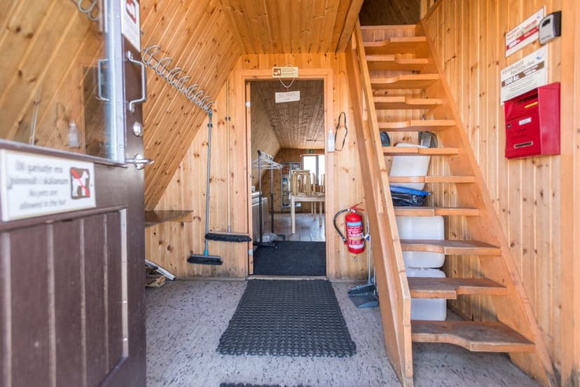 Interior of Fimmvörðuháls hut entrance with wooden walls, stairs, and a doorway to another room.