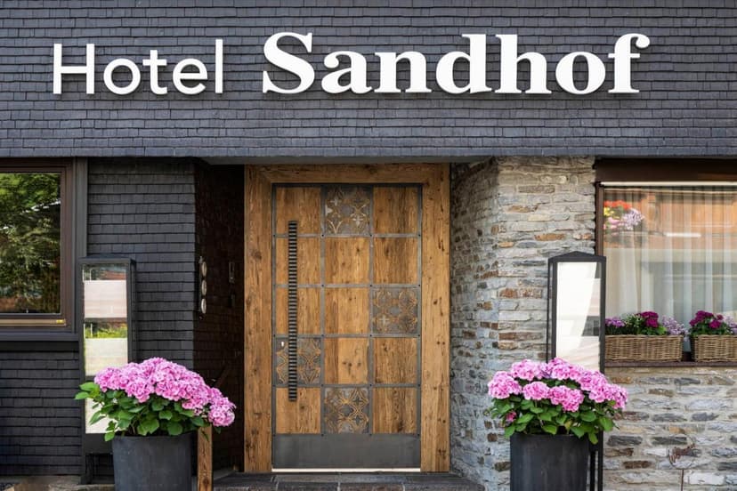 Hotel Sandhof entrance with wooden door, stone facade, and pink hydrangeas
