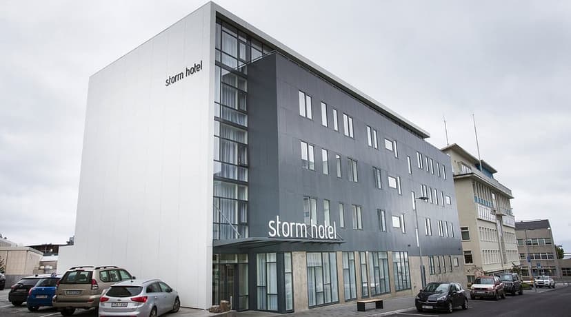 Storm Hotel building with modern white and gray facade parked cars on a cloudy day.