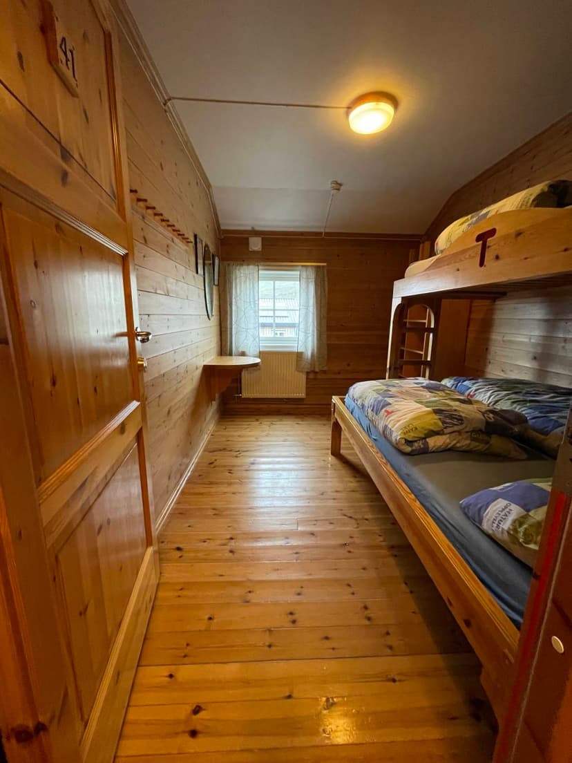 Wooden cabin room with bunk beds, wood paneling, and bright wooden floors, likely Finsehytta.