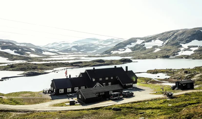 Geiterygghytta mountain lodge by lake with snow-dusted mountains in background