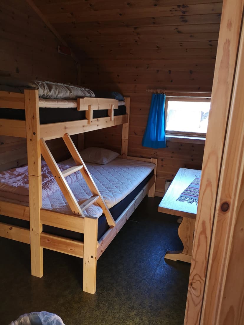 Wooden cabin interior with bunk beds, small window, and wooden table near Steinbergdalshytta.