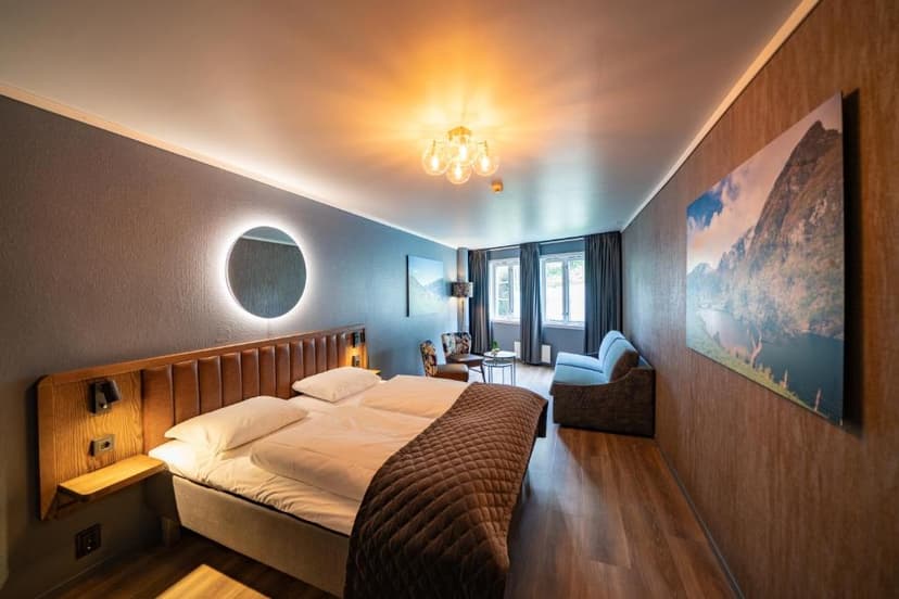 Modern hotel room with large bed, seating area, and mountain artwork, Aurland Fjordhotell