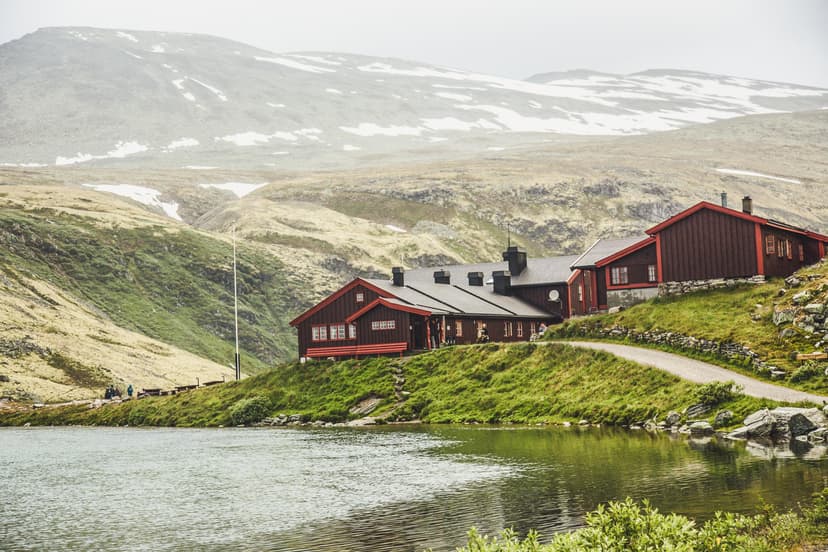 Rondvassbu mountain lodge by lake with snow-dusted peaks in background