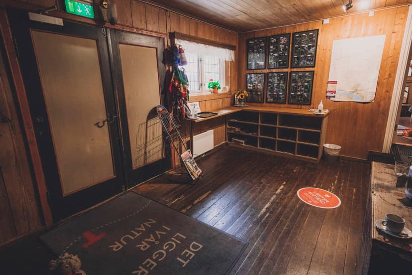 Interior of Gjevillvasshytta hut with wood paneling, storage cubbies, and framed nature displays.