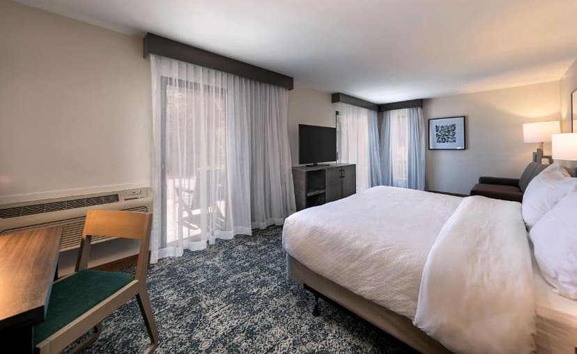 Hotel room at Seacliff Inn Aptos with large bed, TV, and balcony access through sheer curtains.