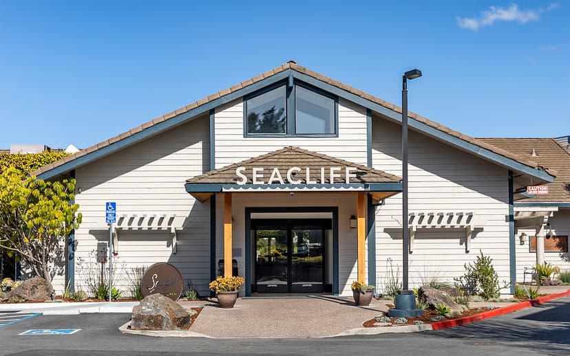 Seacliff Inn entrance in Aptos with light siding, brown roof, and blue sky.