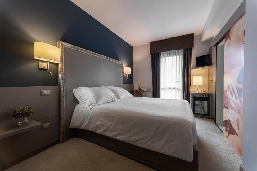 Hotel Doriguzzi bedroom with large bed, dark blue accent wall, and bedside lamps.