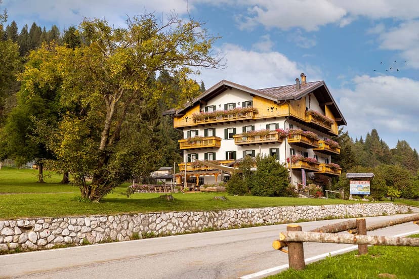 Rifugio Passo Cereda hotel with wooden balconies and flower boxes near a paved road.