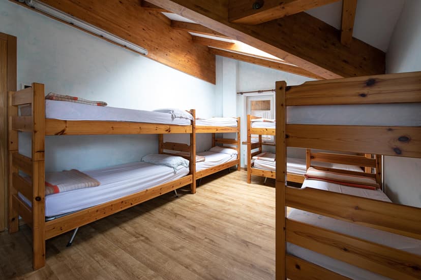 Bunk beds in a wooden-beamed dormitory room at Rifugio Passo Cereda.