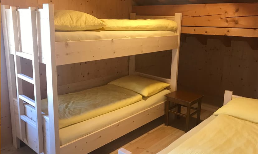 Bunk beds with yellow bedding in a wood-paneled room, near Pisciadù.