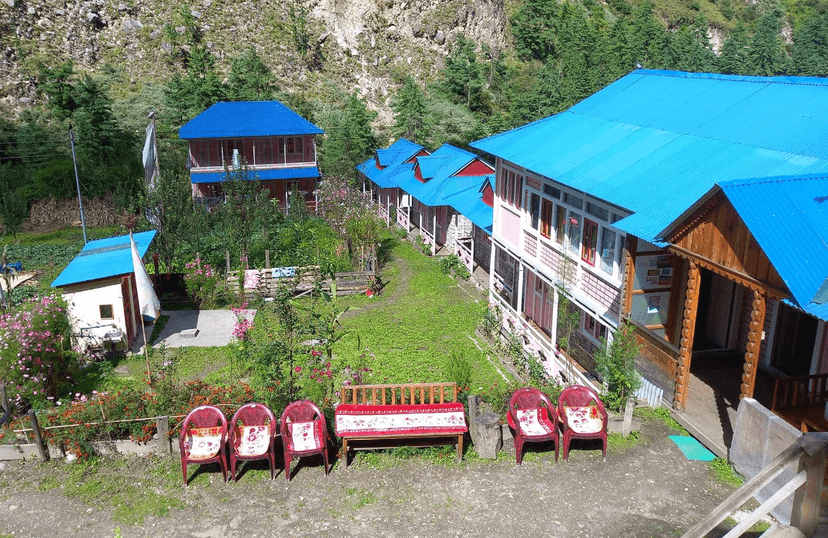 Ghap Cottage Guest House with bright blue roofs nestled in a lush green mountain valley.