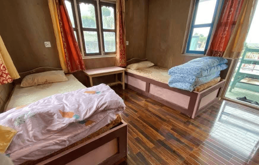 Twin beds in a room with brown walls, wooden floor, and bright curtains near windows