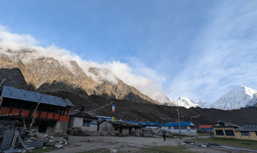 Mountain lodges in a valley with massive, cloud-covered peaks and snow-capped mountains.