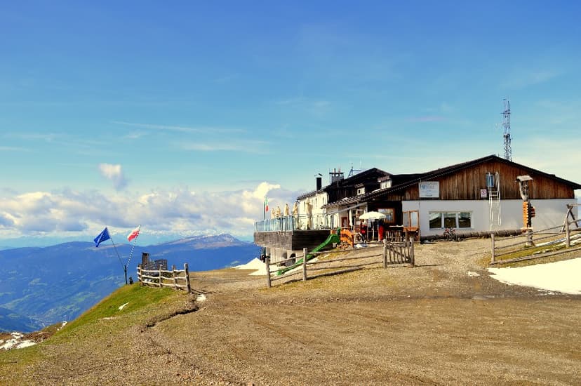 Mountain lodge with terrace overlooking valleys, flying EU and Polish flags, with snow patches.