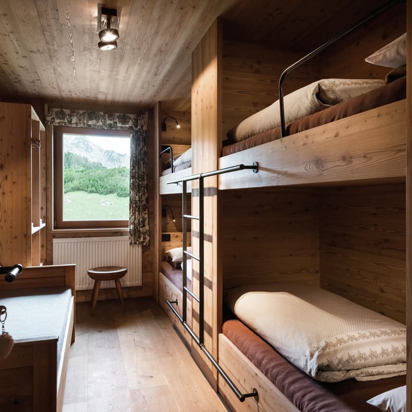 Wooden alpine cabin bedroom with built-in bunk beds and mountain view from window.