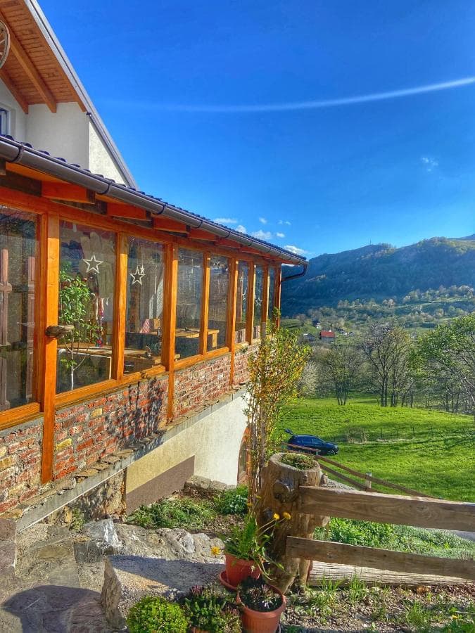 Sunroom with wooden framing overlooking green hills and mountains near Konak-Umoljani.