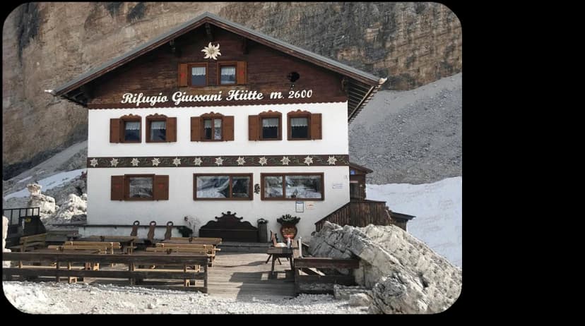 Rifugio Giussani Hütte at 2600m with wooden terrace and rocky alpine setting.